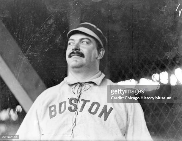 Half-length portrait of Duke Farrell, catcher for the Boston American League team, standing by grandstand concourse netting at South Side Park,...