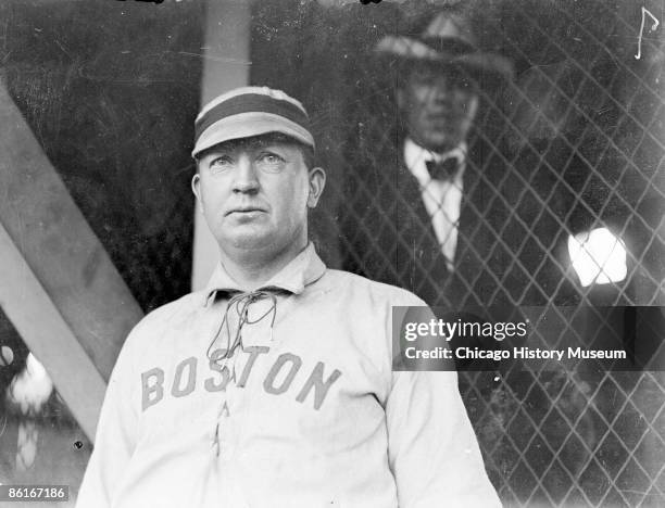 Half-length portrait of Hall of Famer Cy Young, pitcher for the Boston American League team, standing by grandstand concourse netting at South Side...