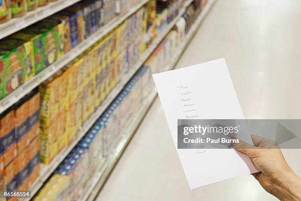woman holding grocery list in grocery store  - shopping list stock pictures, royalty-free photos & images