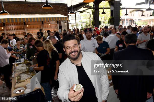 Host Adam Richman poses with a dish being served during Oyster Bash presented by Barnegat Oyster Collective sponsored by Modelo hosted by Adam...