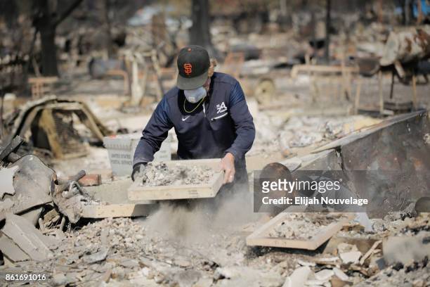 Ed Curzon and his daughter Margaret use sifting trays donated by the Boy Scouts of America to search through the remains of his home for items of...