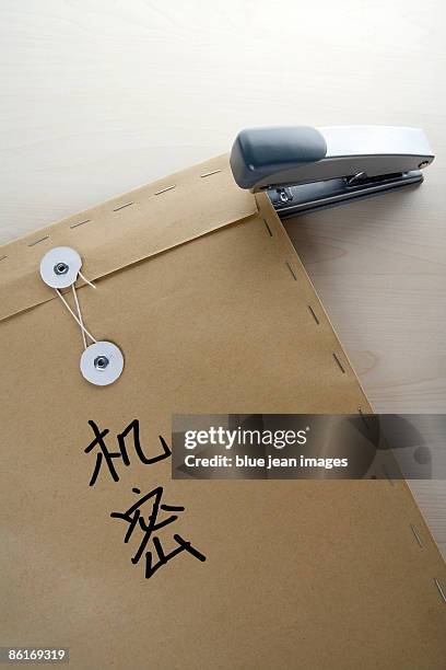 a brown envelope with 'top secret' in chinese characters written on it stapled closed  - brown envelope stock pictures, royalty-free photos & images