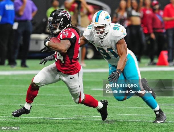 Devonta Freeman of the Atlanta Falcons is pursued by Cameron Wake of the Miami Dolphins at Mercedes-Benz Stadium on October 15, 2017 in Atlanta,...