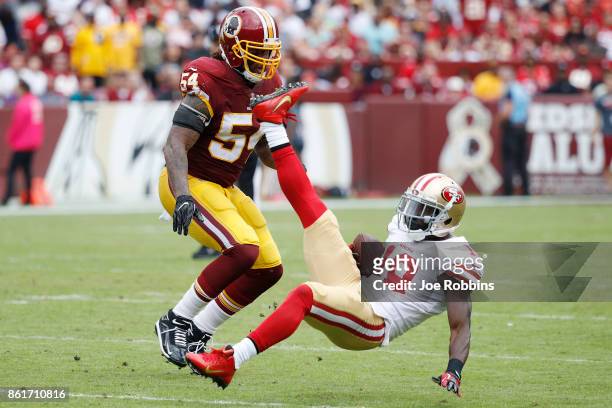 Aldrick Robinson of the San Francisco 49ers is upended after a catch against Mason Foster of the Washington Redskins in the second quarter of a game...