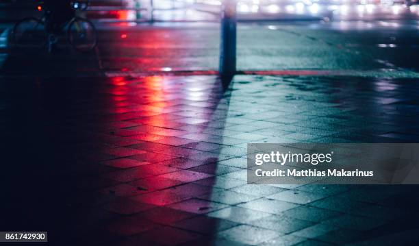 urban city street night lights with reflection and a bicycle - light car night stock-fotos und bilder