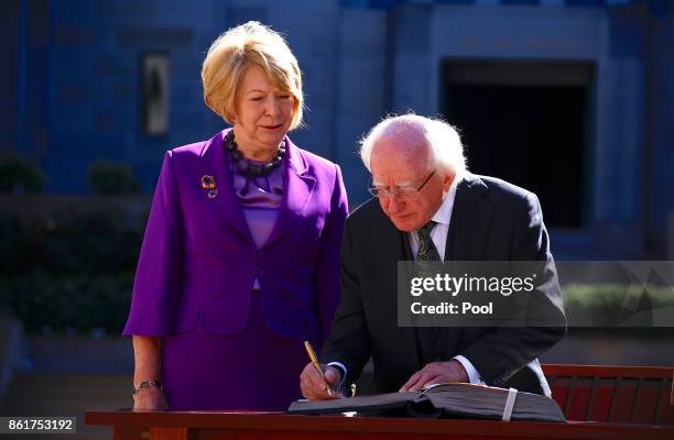 The President of Ireland, Michael Higgins, is watched by his wife Sabina as he signs the official visitor's book at the Australian War Memorial in...