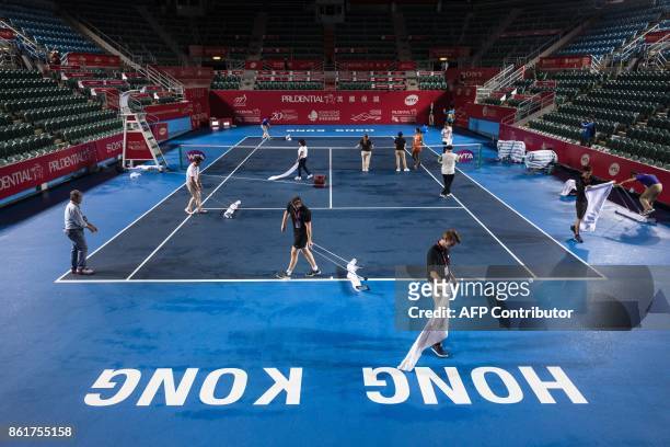 Workers and officials dry the court after heavy from Typhoon Khanun which delayed the start of the women's singles final between Russia's Anastasia...