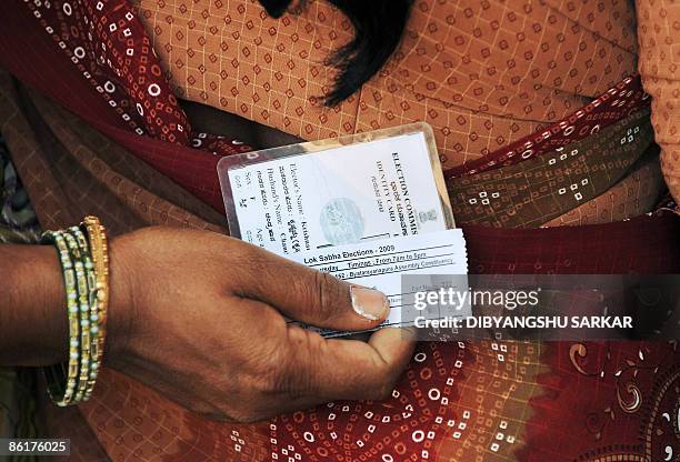 An Indian woman holds her voter identity card and voting slip behind her back as she waits to cast her vote at a polling station in Bangalore on...