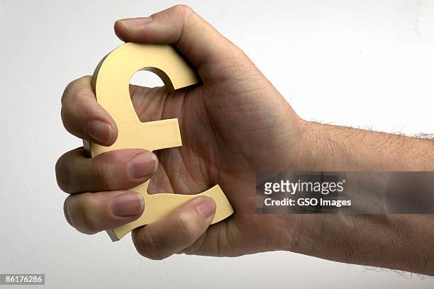 mans hand holds pound sterling symbol as security - squeezing stock pictures, royalty-free photos & images