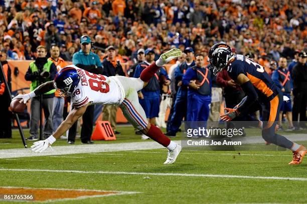 Evan Engram of the New York Giants scores a touchdown as Justin Simmons of the Denver Broncos defends during the second quarter of the on Sunday,...