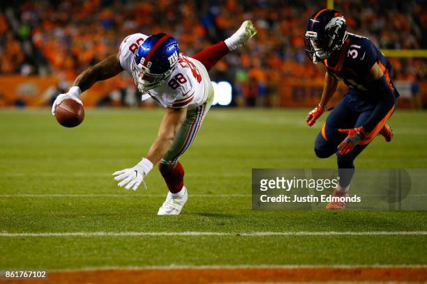 Tight end Evan Engram of the New York Giants dives into the end zone for a touchdown after beating strong safety Justin Simmons of the Denver Broncos...