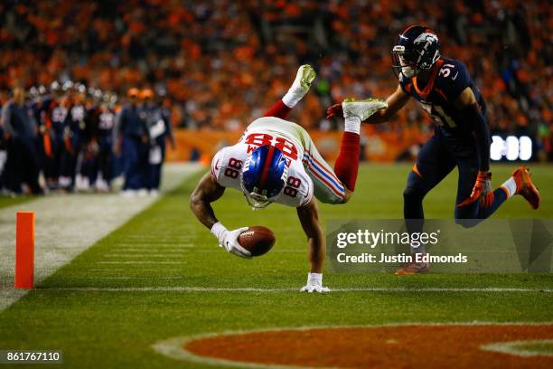 Tight end Evan Engram of the New York Giants dives into the end zone for a touchdown after beating strong safety Justin Simmons of the Denver Broncos...