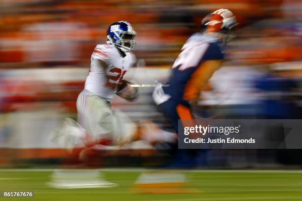 Running back Orleans Darkwa of the New York Giants runs with the football for a long gain as strong safety Justin Simmons of the Denver Broncos...