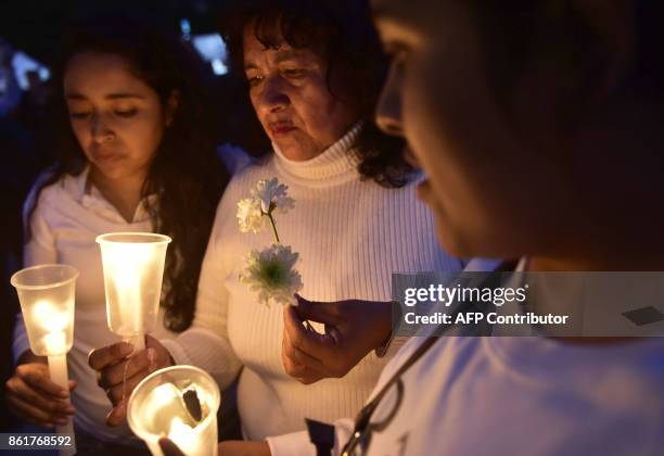 Women hold candles and flowers during a tribute for the victims of Mexico's last earthquake at the esplanade of the Revolution Square in Mexico City,...