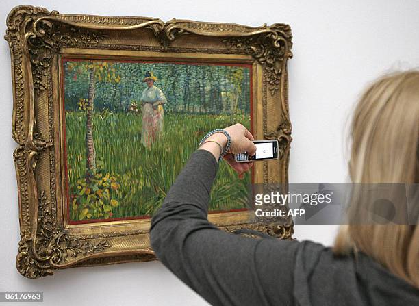Woman takes a picture of the painting, "A Woman Walking in a Garden" by Dutch artist Vincent van Gogh, as part of the exhibition "Vincent van Gogh...