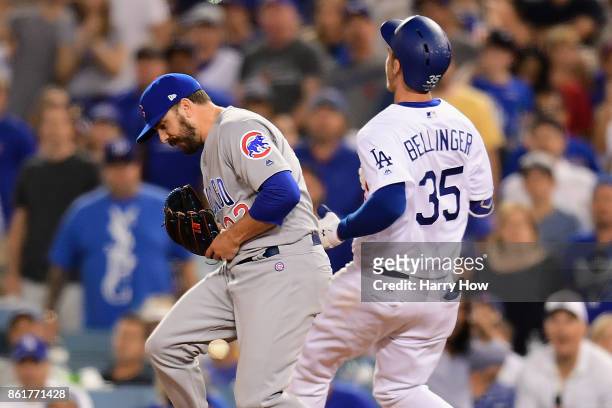 Brian Duensing of the Chicago Cubs drops the throw to first base as Cody Bellinger of the Los Angeles Dodgers is safe after hitting a single in the...