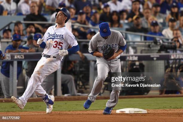 Brian Duensing of the Chicago Cubs drops the throw to first base as Cody Bellinger of the Los Angeles Dodgers is safe after hitting a single in the...