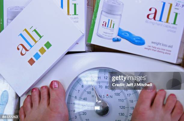 In this photo illustration, a woman wighs herself at G W Allan chemists, where the Alli slimming pill is stocked on April 23, 2009 in Edinburgh,...