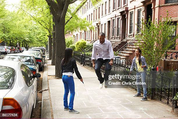 father and daughters playing jump-rope - hopscotch stock pictures, royalty-free photos & images