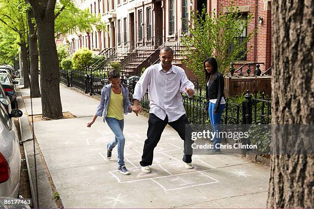 father & daughters playing hop-scotch - hopscotch stock pictures, royalty-free photos & images