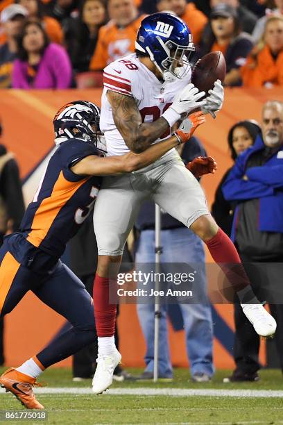 Justin Simmons of the Denver Broncos hits Evan Engram of the New York Giants as he attempts to wrangle the ball during the third quarter of the on...