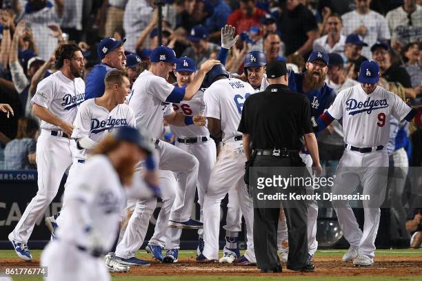 Yasiel Puig of the Los Angeles Dodgers celebrates with teammates as he scores a run after Justin Turner hit a three-run walk-off home run in the...