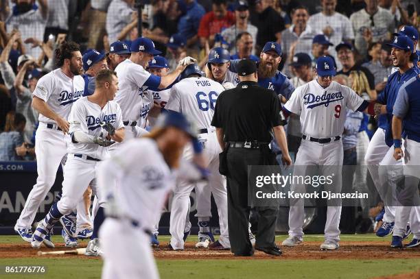 Yasiel Puig of the Los Angeles Dodgers celebrates with teammates as he scores a run after Justin Turner hit a three-run walk-off home run in the...