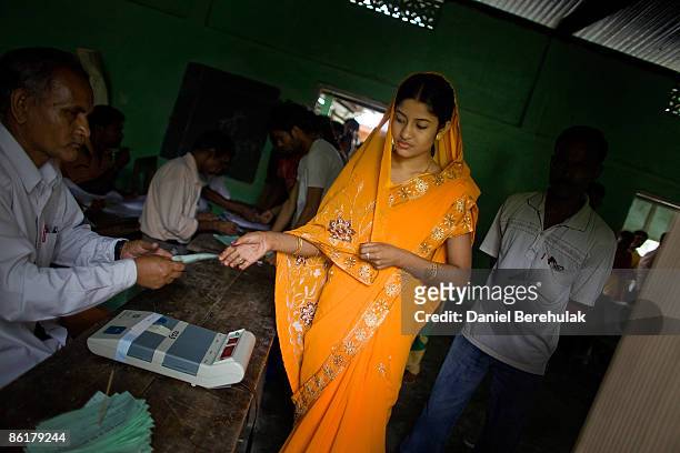 An Indian woman hands in her voting slip before casting her vote at a polling station on April 23, 2009 in the Muslim dominated town of Mukalmua,...