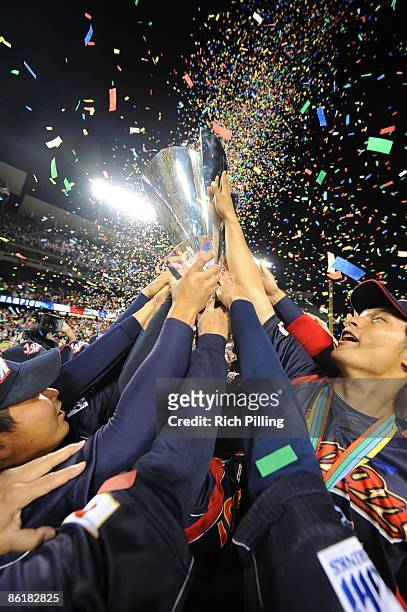 Members of team Japan touch the trophy after defeating Korea in the World Baseball Classic final game at Dodger Stadium in Los Angeles, California on...