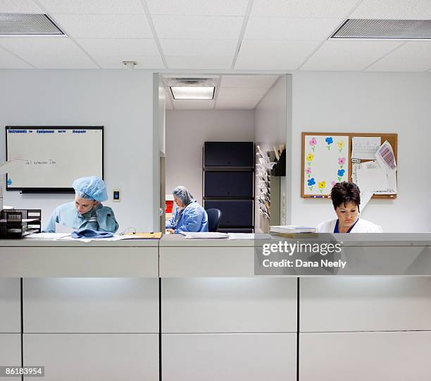 charge nurse & scrub techs sitting at or desk - medical chart stock pictures, royalty-free photos & images