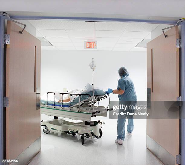 nurse wheeling patient to surgery or - stretcher photos et images de collection