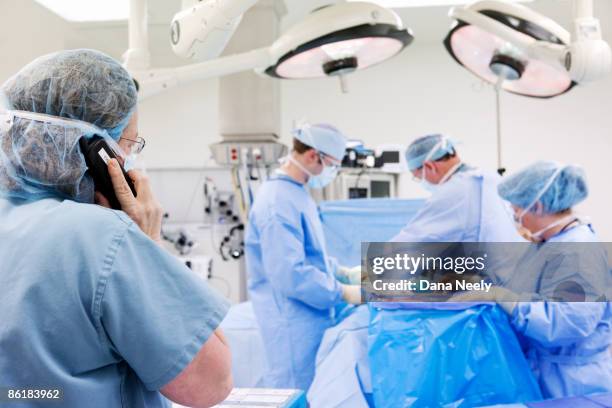 nurse calling patients family during surgery - op-mundschutz stock-fotos und bilder