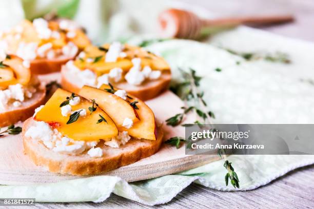 homemade bruschetta with nectarines, salted feta cheese, dried thyme and honey on a wooden board, selective focus - crostini stock pictures, royalty-free photos & images