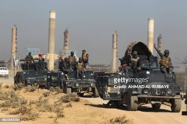 Iraqi forces drive past an oil production plant as they head towards the city of Kirkuk on October 16, 2017.