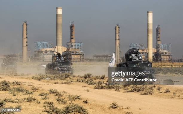 Iraqi forces drive past an oil production plant as they head towards the city of Kirkuk on October 16, 2017. / AFP PHOTO / AHMAD AL-RUBAYE
