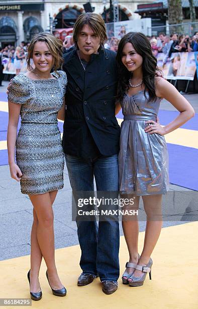 Actress Miley Cyrus, , and her on and off screen father Billy Ray, with fellow US actress Demi Lovato, , pose after arriving in London's Leicester...