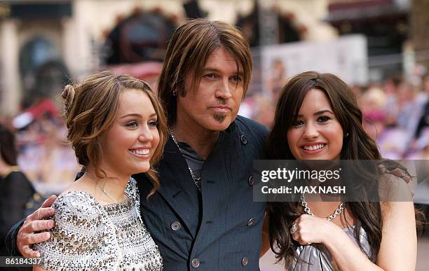 Actress Miley Cyrus, , and her on and off screen father Billy Ray, with fellow US actress Demi Lovato, , pose after arriving in London's Leicester...