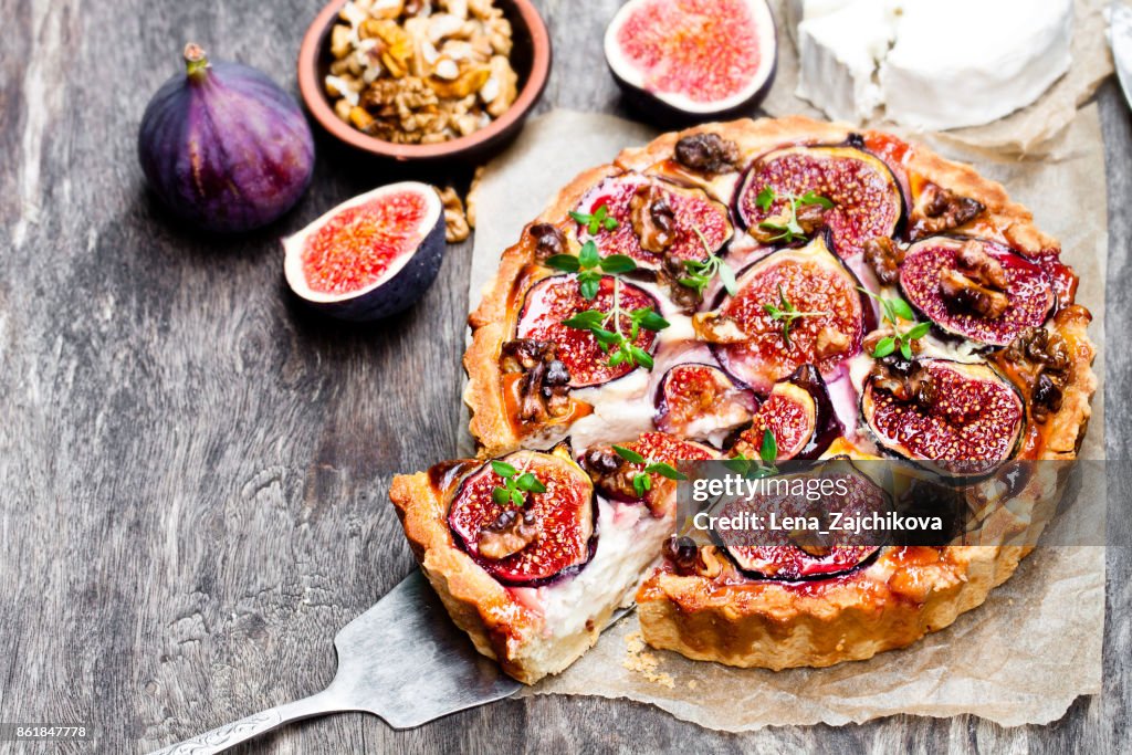 Delicious  tart with fresh figs and goat cheese on rustic wooden table