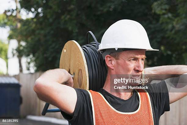 lineman carrying a cable spool - cable installer stock pictures, royalty-free photos & images