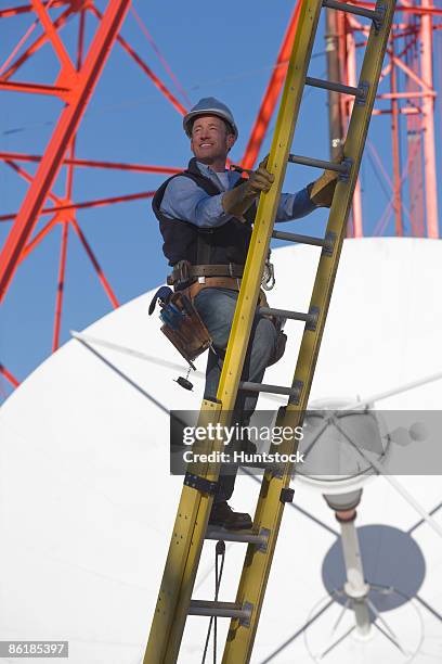 cable lineman climbing a ladder to repair transmission line - torre di trasmissione a microonde foto e immagini stock