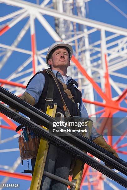 cable lineman standing on a ladder to repair transmission line - torre di trasmissione a microonde foto e immagini stock