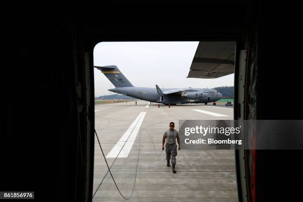 Member of the U.S. Air Force walking in front of a C-17 Globemaster III aircraft, manufactured by Boeing Co., is seen through a doorway of another...