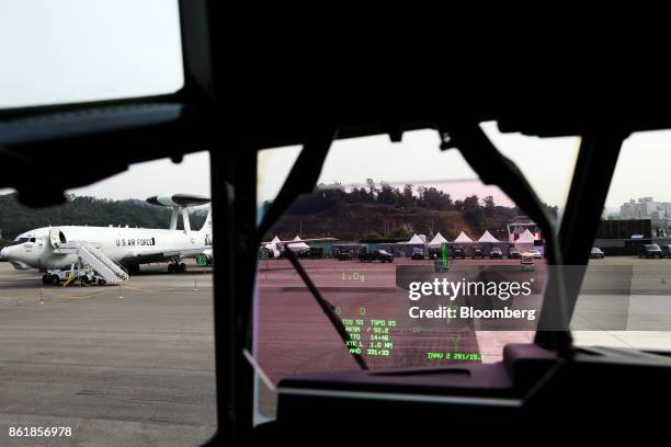 Air Force E-3 AWACS aircraft, manufactured by Boeing Co., sitting on the tarmac is seen through the heads up display of a U.S. Air Force C-130J Super...