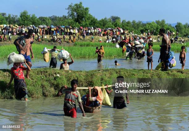 Rohingya refugees carry a woman over a shallow canal after crossing the Naf River as they flee violence in Myanmar to reach Bangladesh in Palongkhali...