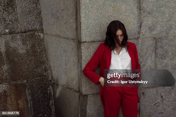 woman in red pantsuit standing near the brick wall - acessórios de moda imagens e fotografias de stock