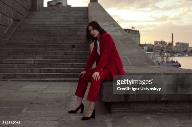 woman in red pantsuit  walking in the city - pant suit stockfoto's en -beelden