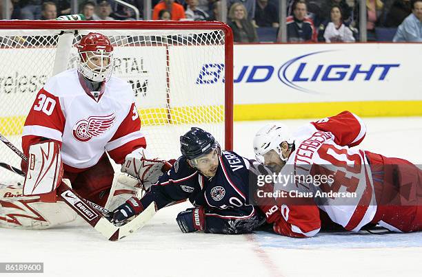 Antoine Vermette of the Columbus Blue Jackets is tackled by Henrik Zetterberg in front Chris Osgood of the Detroit Red Wings during Game Four of the...