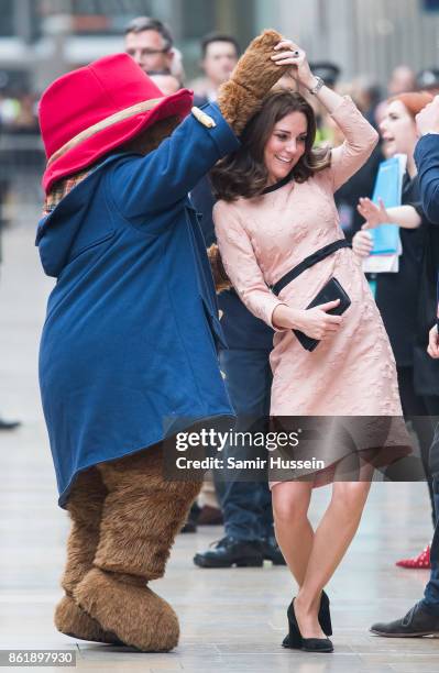 Catherine, Duchess of Cambridge dances with Paddington Bear as she attends the Charities Forum Event on board the Belmond Britigh Pullman train at...