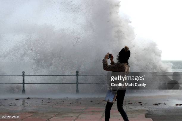Woman take a photograph as waves crash up onto Penzance seafront on October 16, 2017 in Cornwall, England. The hurricane comes exactly 30 years after...