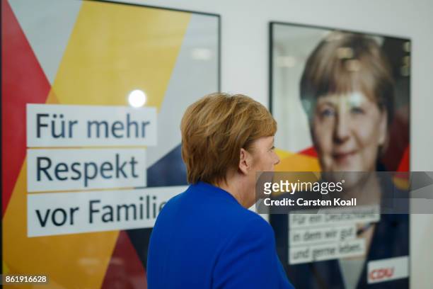 German Chancellor and leader of the German Christian Democrats Angela Merkel passes a picture of her after leaving a press conference together with...